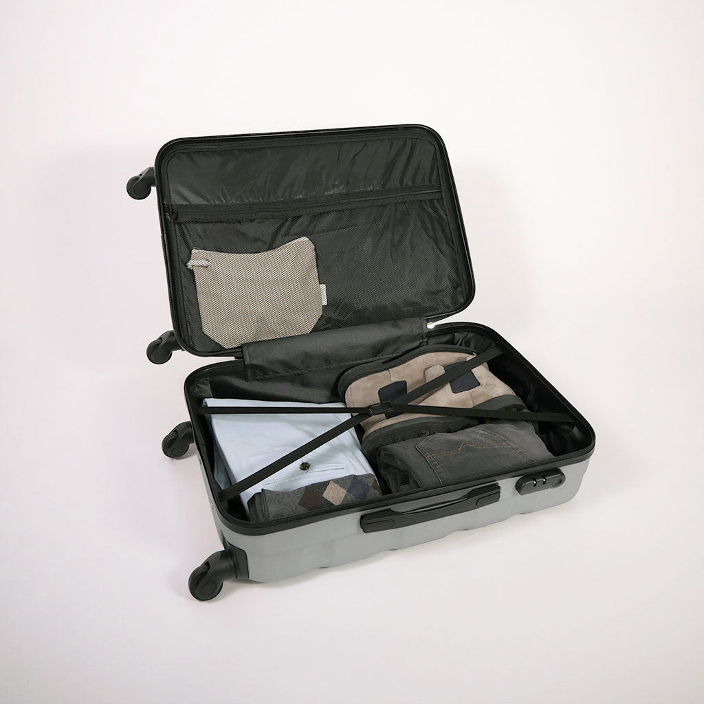 Valigia grigia aperta piena di vestiti, con dettaglio di cinghie estensibili elastiche, doppio fondo e tasca con zip