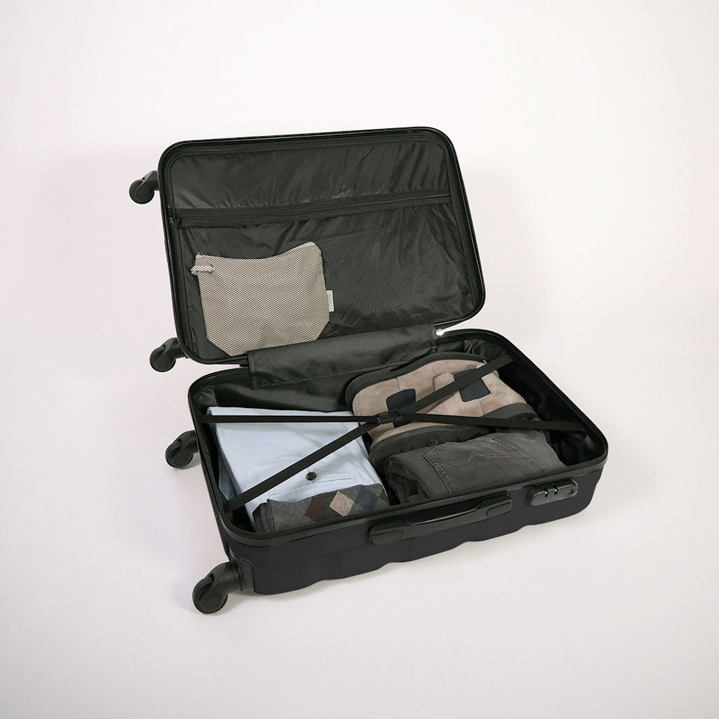 Valigia nera aperta piena di vestiti, con dettaglio di cinghie estensibili elastiche, doppio fondo e tasca con zip