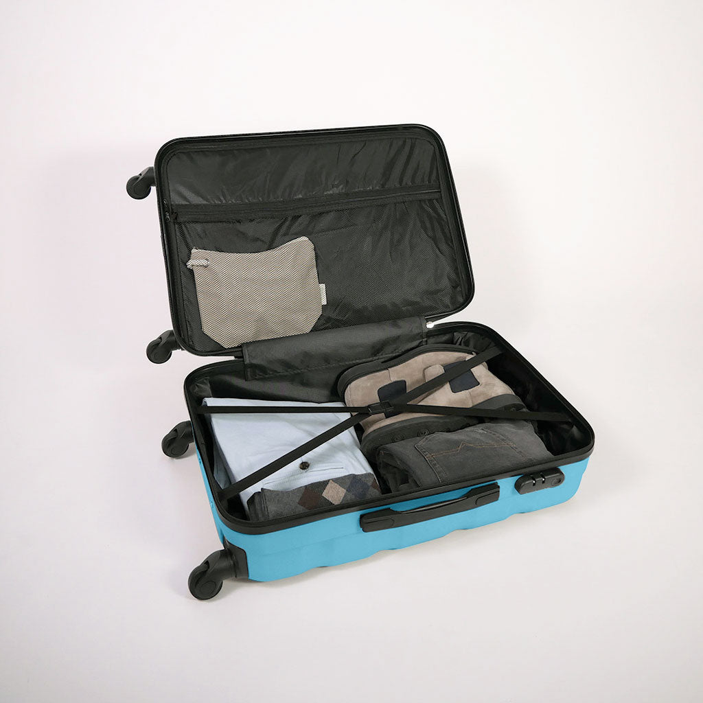 Valigia azzurra aperta piena di vestiti, con dettaglio di cinghie estensibili elastiche, doppio fondo e tasca con zip